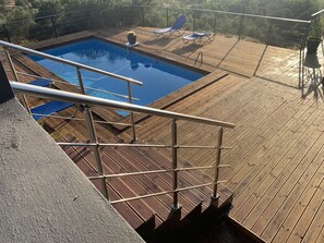 Um deck de madeira com piscina e espreguiçadeiras.