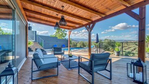 Eine Holzterrasse mit Gartenmöbeln, einem Pool und Blick auf die Landschaft.