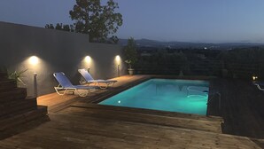 Ein Schwimmbecken mit zwei Liegestühlen und einer Holzterrasse.
