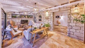A cozy living room with a stone wall, a flat-screen TV, comfortable seating, and decorative lighting. - Caliza Alacati (Cesme)