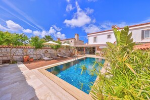 A swimming pool with a wooden deck, lounge chairs, and umbrellas. - Caliza Alacati (Cesme)