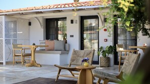 A covered outdoor seating area with a wooden table, chairs, and a small table with a vase. - Caliza Alacati (Cesme)