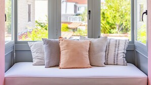 A window seat with cushions, overlooking a garden and buildings. - Caliza Alacati (Cesme)