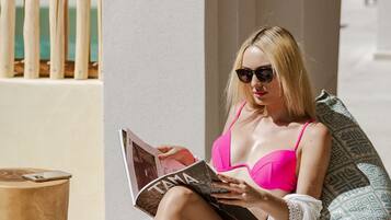 Una persona sentada en un sillón de peluche estampado, leyendo una revista.