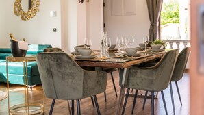 A dining area with a wooden table set for six, surrounded by grey upholstered chairs. A gold-framed mirror hangs on the wall above the table. - Villa Skyfall (Bibinje)