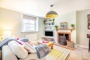 A living room with a sofa, a television, a fireplace, and shelves with decorative items.
