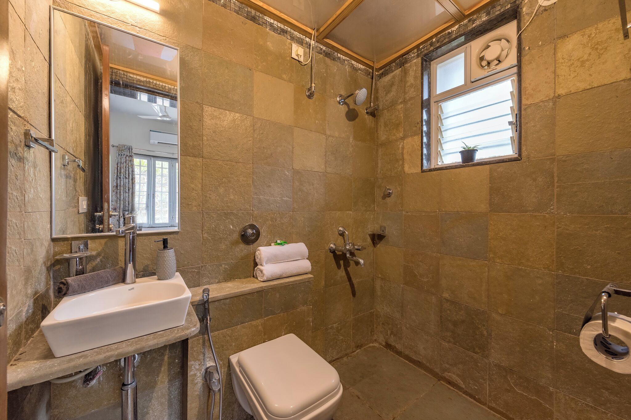 A bathroom with a sink, mirror, towel rack, shower, and toilet.