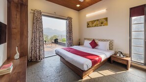 A bedroom with a bed, a nightstand, a ceiling fan, a window with curtains, and a view of the outdoors. - CosmicStays GreyStone Villa Mountain View & Dam (Paud)