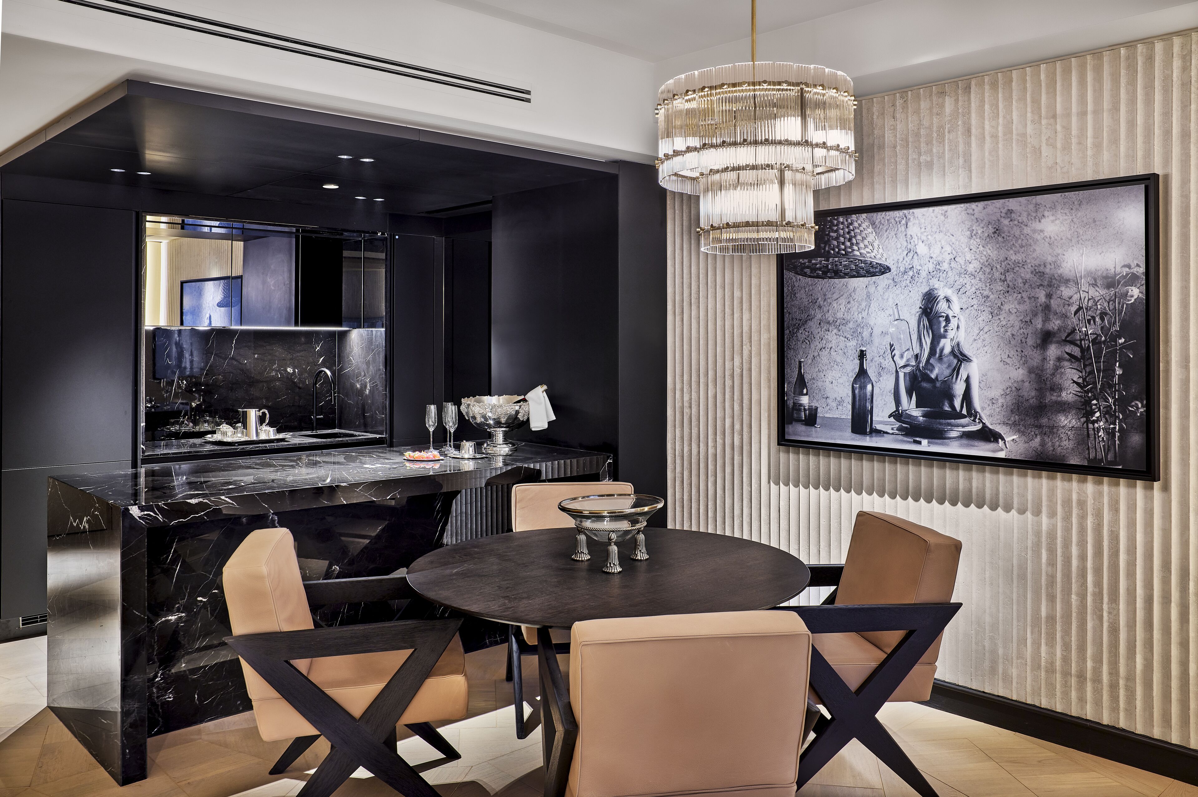 A modern dining area with a marble countertop, black and beige chairs, a round table, and a large framed artwork on the wall.