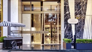 A modern hotel entrance with a marble facade, a glass door, and a sign reading "VAKKO L'ATELIER HOTEL". - Vakko Hotel and Residence (Istanbul)