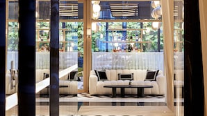 A modern hotel lobby with a seating area, a bar, and large windows offering a view of the outdoors. - Vakko Hotel and Residence (Istanbul)