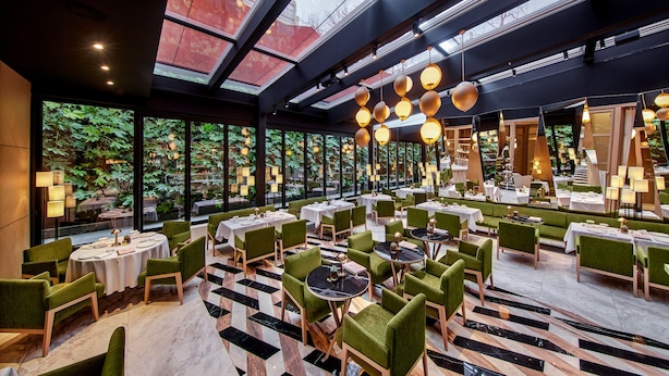 A restaurant with round tables and green chairs, large windows, and hanging spherical lights. - Vakko Hotel and Residence (Istanbul)