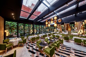 A restaurant with round tables and green chairs, large windows, and hanging spherical lights. - Vakko Hotel and Residence (Istanbul)