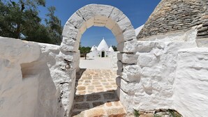 Un camino de piedra con arco que conduce a un edificio blanco de tejado de piedra.