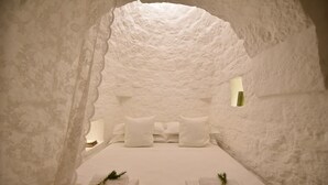 Una habitación con forma de iglú, con una cama, almohadas y una pequeña ventana.