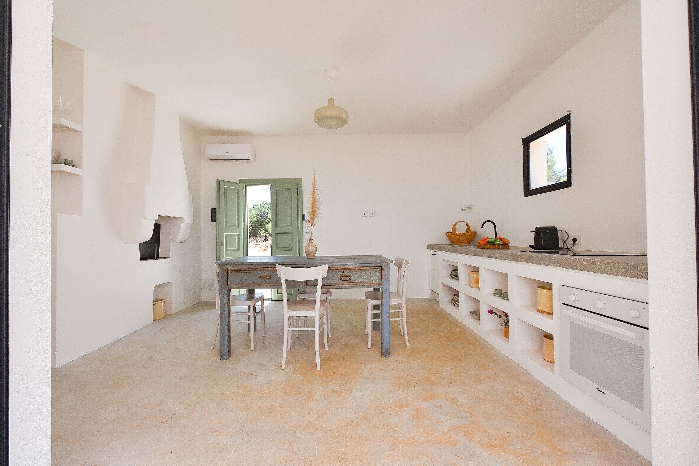 Une cuisine avec une table à manger, des chaises, un four blanc et une fenêtre.