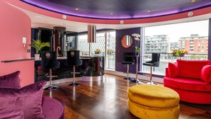 Un intérieur moderne aux couleurs pourpre et rouge, comprenant un canapé, un pouf jaune et un divan rouge.