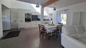 Une cuisine moderne avec des meubles blancs, une table à manger avec des chaises et un canapé blanc.