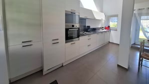 Une cuisine moderne avec des meubles blancs, des appareils en acier inoxydable et un puits de lumière.