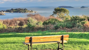 Un banc situé dans un espace verdoyant, offrant une vue sur la mer et les îles.