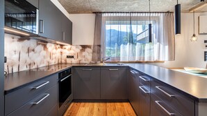 Eine moderne Küche mit dunklen Schränken, Holzboden und einem großen Fenster mit Bergblick.