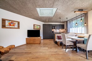 A modern kitchen with a skylight, wooden cabinets, and a dining area with a table and chairs. - Holiday Apartment 'Chalet Riad 2' with Mountain View and Outdoor Whirlpool (St. Martin / Saltaus)