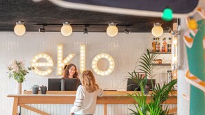 Una recepción con un gran letrero iluminado que dice 'eklo', una computadora y una planta.