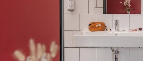 A bathroom with a white sink, a mirror, and a red wall.