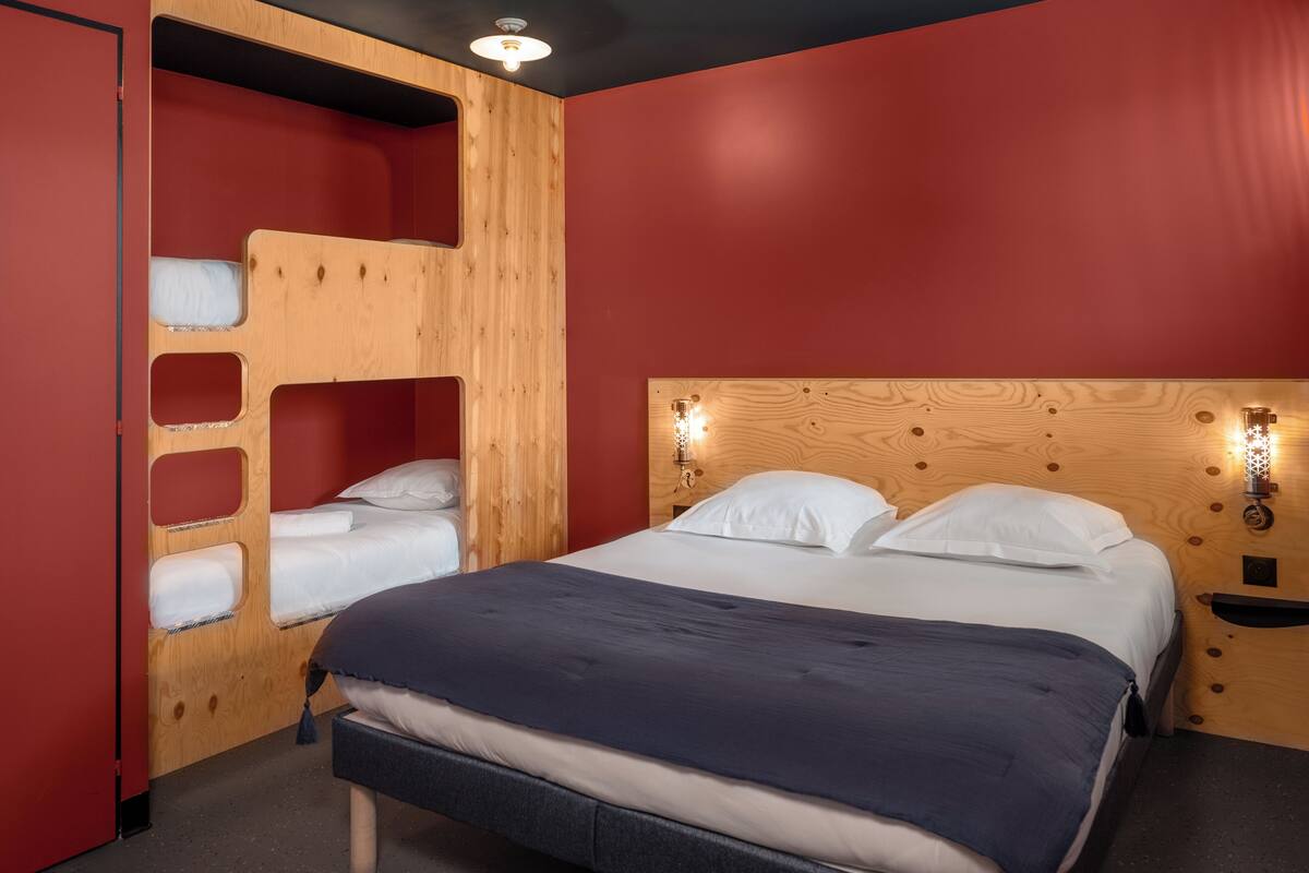 Una cama litera con cabecera de madera y una mesita de noche con lámpara.