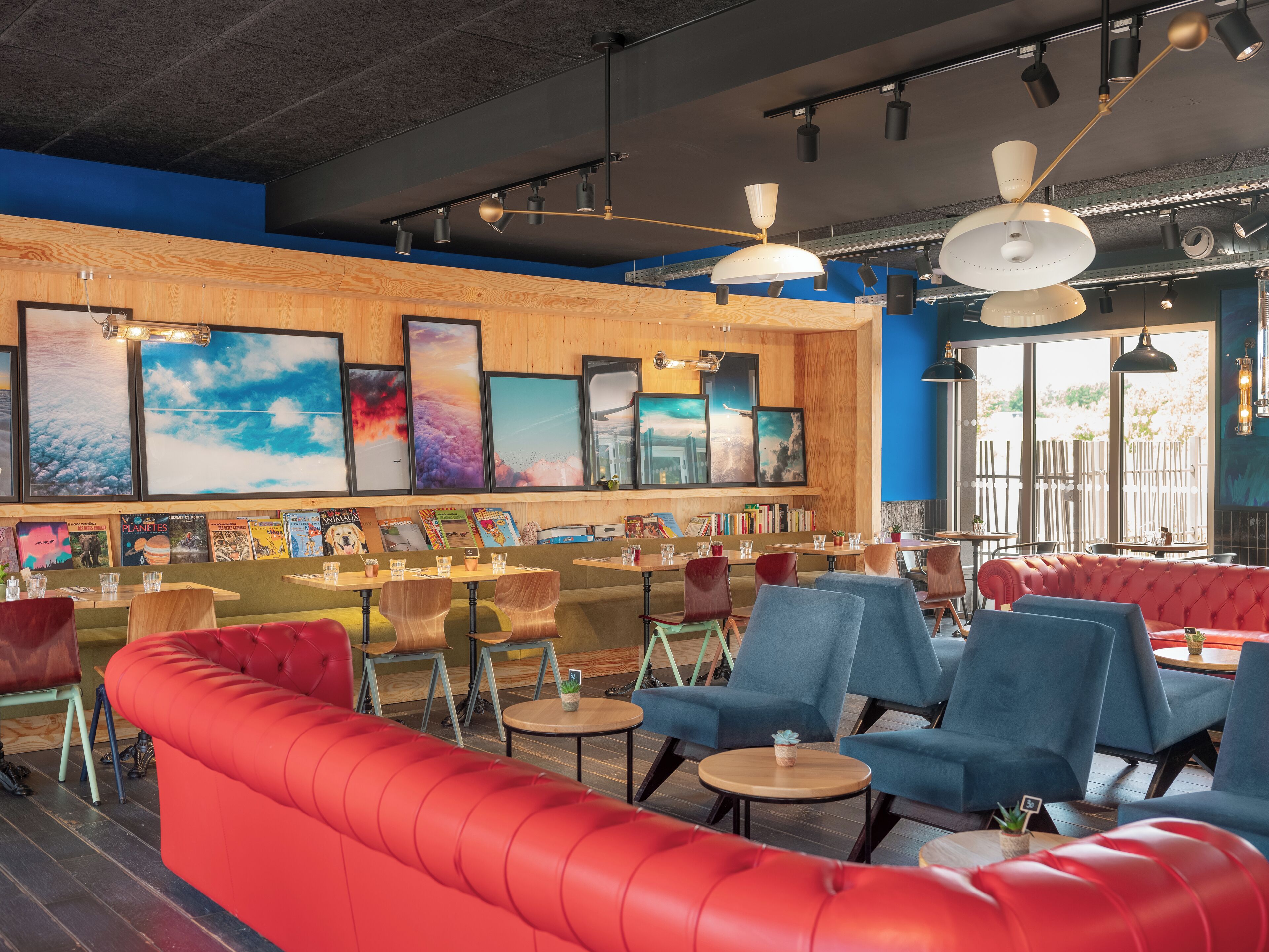 A modern restaurant interior with red seating, wooden accents, and artwork on the walls.