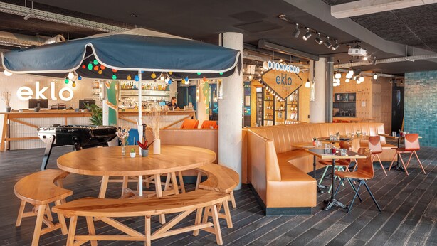 Zona de bar moderna con mostrador, asientos y un cartel que dice 'Welcome'.