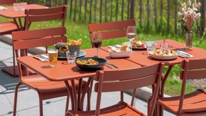 Una mesa al aire libre con comida y bebidas, rodeada de sillas.