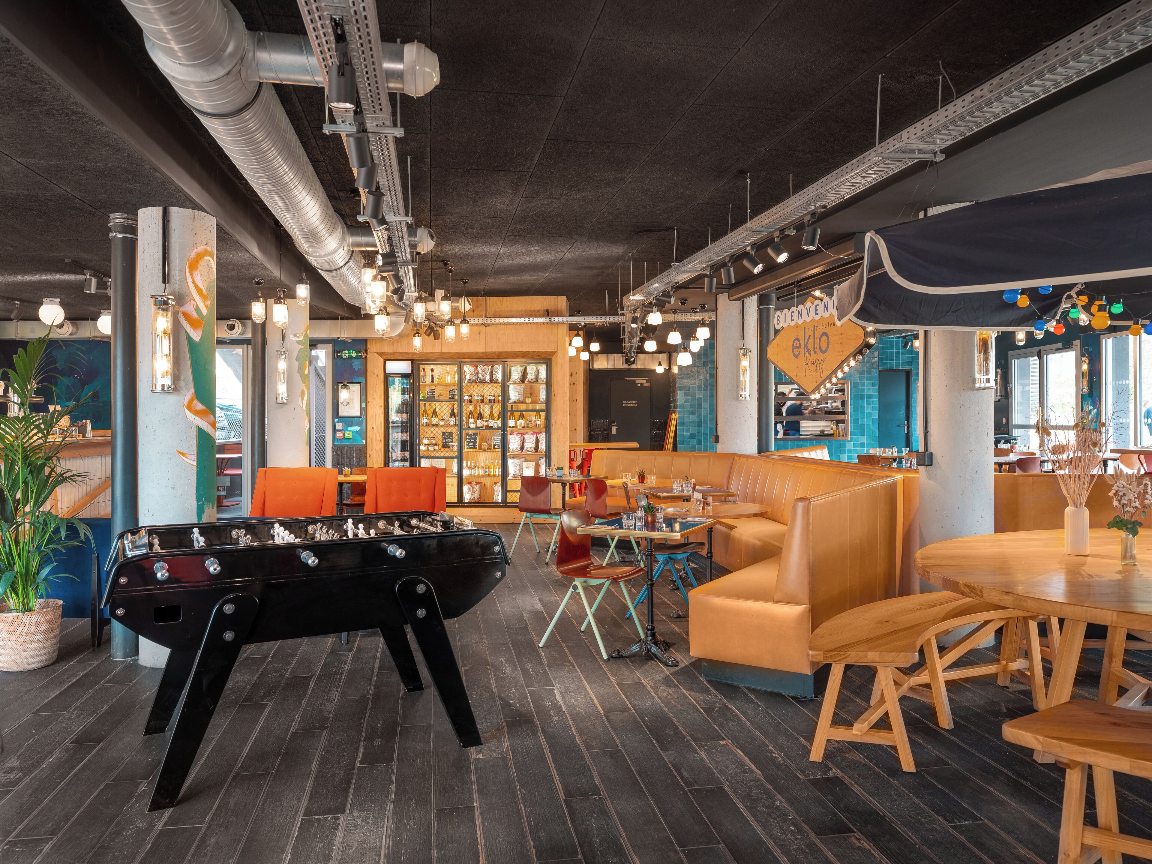 Un espacio interior acogedor con mesa de fútbol de mesa, zonas de estar y un bar.
