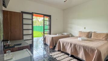 A hotel room with a bed, a desk, a chair, a ceiling fan, and a view of the outdoors.