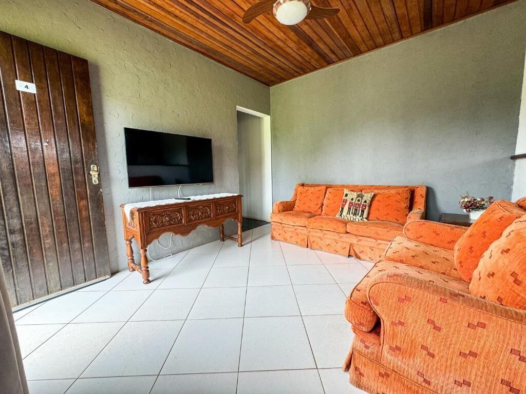 Una sala de estar con techo de madera, televisor, sofá y aparador.