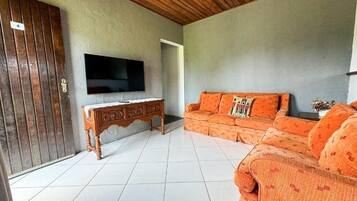 Una sala de estar con techo de madera, televisor, sofá y aparador.