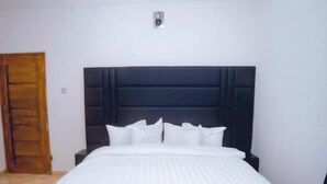 Un dormitorio moderno con una cama grande, un cabecero oscuro y una mesita de noche pequeña.