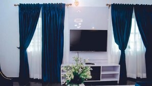 Una sala de estar moderna con una mesa redonda blanca, un televisor de pantalla plana montado en la pared y una planta decorativa sobre la mesa.