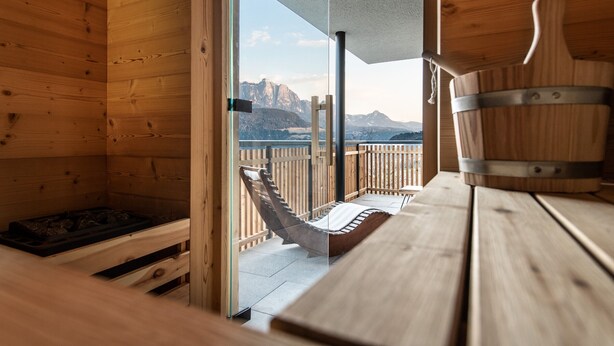 Eine Holzhütte mit einer Hängematte, einem Holztisch und Blick auf die Berge.