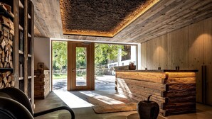 Ein modernes Interieur mit einem hölzernen Empfangsschalter, einer großen Glasdoor zur Außenseite und Blick auf Grünflächen.