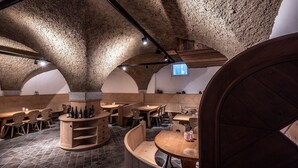 Ein rustikales Interieur mit Steinwänden, Holzmöbeln und einer zentralen Steinkonstruktion.