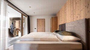 Ein modernes Schlafzimmer mit einem großen Bett, Holzwandverkleidung und Blick durch eine Schiebetür.