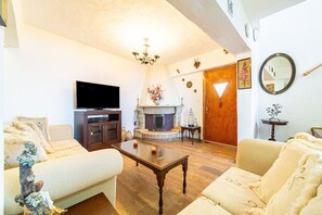 Un salon avec une cheminée, un téléviseur et un canapé.