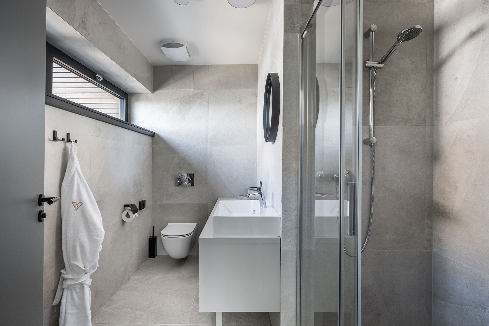 A modern bathroom with a glass shower enclosure, a white sink, and a toilet.