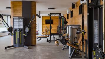 Een moderne sportschool met diverse fitnessapparaten, waaronder een gewichtmachine, een bankdrukapparaat en een kabeltrekapparaat.