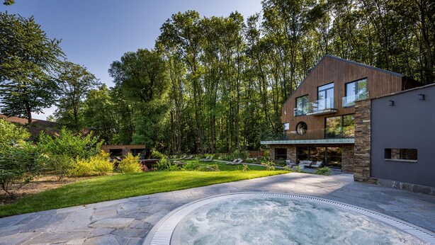 A modern house with a hot tub, stone patio, and lush greenery. - Vista Resort Prague (Prague)