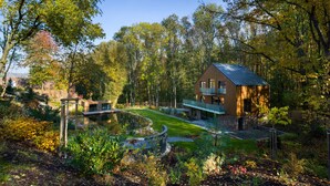 A modern house with a large deck, surrounded by a pond and dense trees. - Vista Resort Prague (Prague)