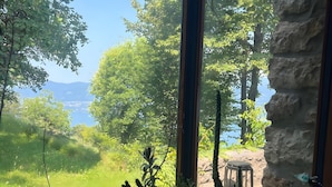 A room with a large window overlooking a lush garden and a body of water.