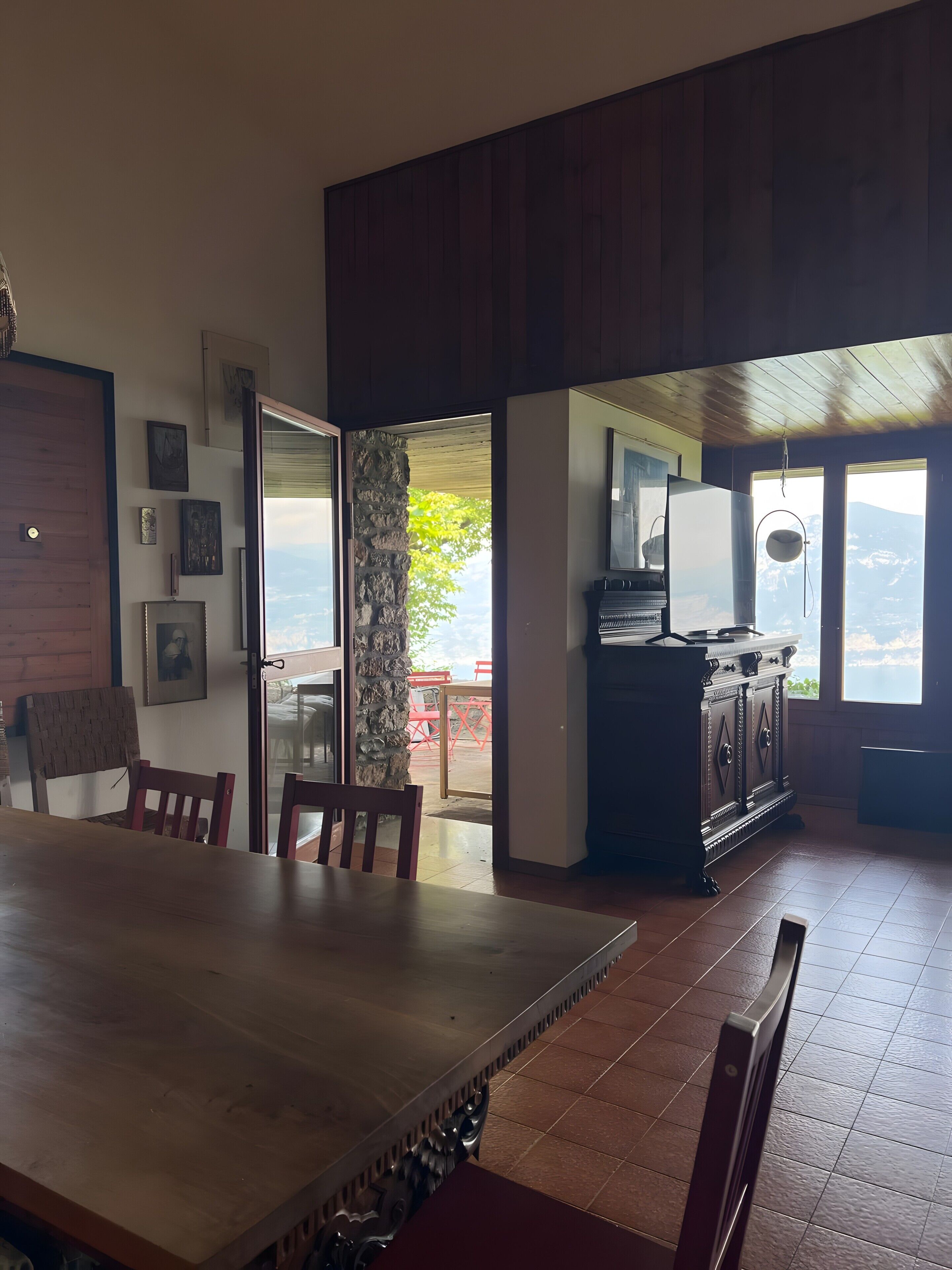 A dining area with a wooden table and chairs, a stone pillar, and a view of the outdoors.