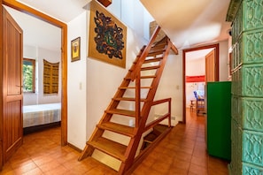Eine Holztreppe in einem Zimmer mit einem Bett, einem grünen Schrank und einem Gemälde an der Wand.
